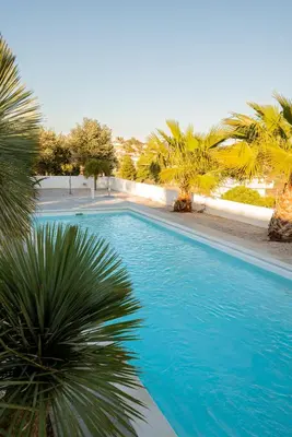 a blue swimming pool with palm trees around it at Villa Tata - Private Pool, Garden & Mountain View near the Sea in Metókhi