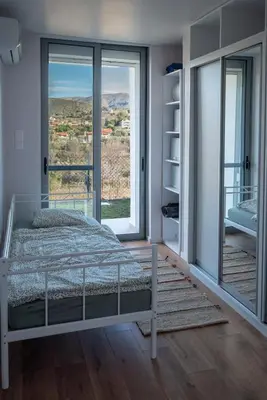 a bedroom with a bed and a large window at Villa Tata - Private Pool, Garden & Mountain View near the Sea in Metókhi