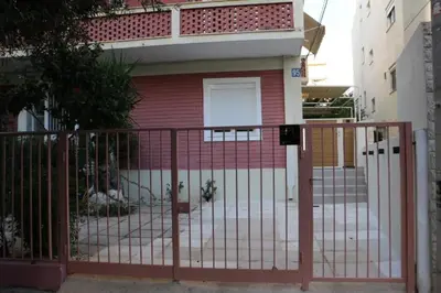 a red metal gate in front of a house at FaliroRelax F1 in Athens