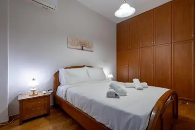 a bedroom with a bed with white sheets and wooden cabinets at Authentic Athens stay in Kypseli by ΜΡS in Athens