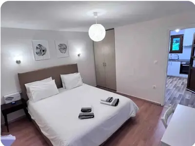 a bedroom with a large white bed with a clock on it at Glyfada center apartment with private yard in Athens