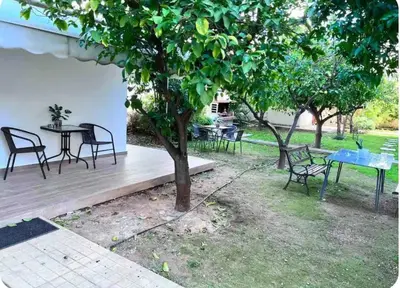 a wooden deck with chairs and tables and a tree at Glyfada center apartment with private yard in Athens