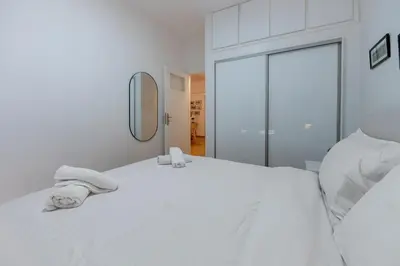 a white bedroom with a bed with towels on it at Colorful Koukaki Apartment Near the Acropolis in Athens