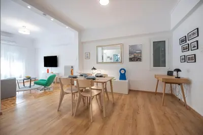 a white living room with a table and chairs at Colorful Koukaki Apartment Near the Acropolis in Athens