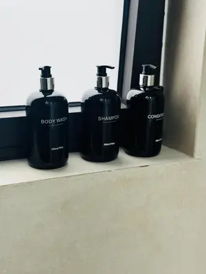 three bottles of soap on a shelf in a bathroom at Glyfada Unique Luxury & Spacious Apartment in Athens