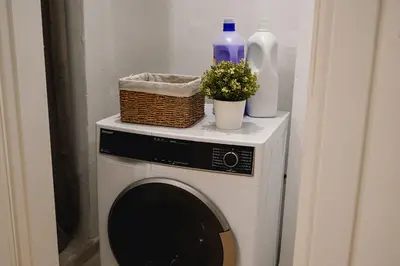 a washing machine with bottles and flowers on top of it at Portside Residence Piräus in Piraeus