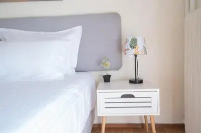 a bedroom with a white bed and a nightstand with a lamp at ANDIE Agios Eleftherios in Athens