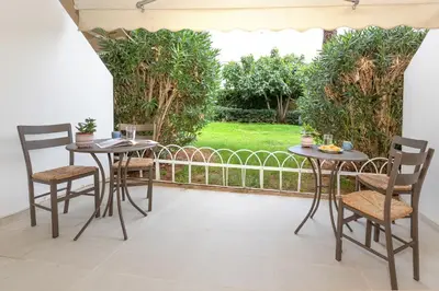two tables and chairs on a patio with trees at Riviera Garden House in Athens