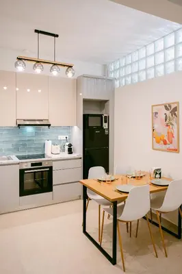 a kitchen with a wooden table and white chairs at Spacious 2BR house in Nea Smyrni in Athens