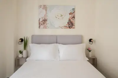 a white bedroom with a white bed with two lamps at ANDIE Athens Koukaki in Athens