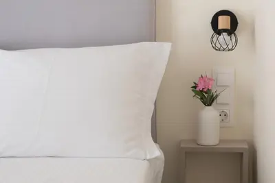 a bed with a white pillow and a vase with flowers at ANDIE Athens Koukaki in Athens