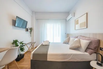 a bedroom with a bed and a desk and a tv at Prime City Stay by Cloudkeys in Athens