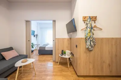 a living room with a couch and a tv on a wall at Prime City Stay by Cloudkeys in Athens