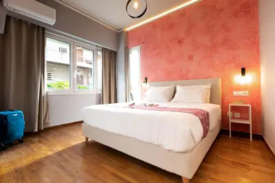 a bedroom with a large bed with a red wall at DP Homes Acropolis Promenade in Athens