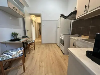 a kitchen with wooden floors and white cabinets at Upper Kypseli Nest Apartment in Athens