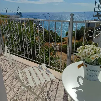 a table and a chair on a balcony with the ocean at Kalimera Aegina in Agia Marina Aegina