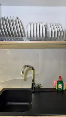 a kitchen counter with a sink and a shelf with plates at Modern 2BR Garden Apartment in Faliro Sleeps 5 in Athens