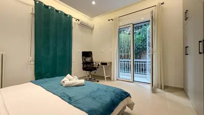 a bedroom with a bed and a chair and a window at Modern 2BR Garden Apartment in Faliro Sleeps 5 in Athens