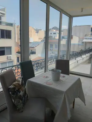 a table and chairs with a white table and windows at Ermou 44 - 2bdr apartment in Athens