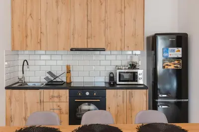 a kitchen with wooden cabinets and a black refrigerator at Artistic Luxury with Acropolis View in Psirri Monastiraki in Athens