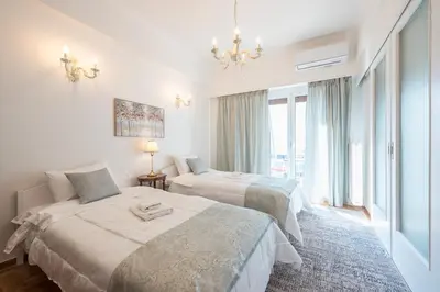 a bedroom with two beds and a chandelier at Sun-Kissed Koukaki Apartment City Views in Athens