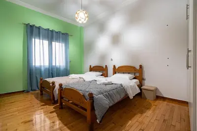 two beds in a room with green walls and wooden floors at Central Nea Smyrni 2BR Apt-Near Transport by ΜΡS in Athens