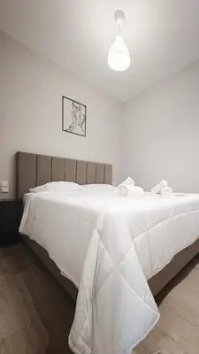 a white bedroom with a large bed with white sheets at Dream House Egaleo in Athens