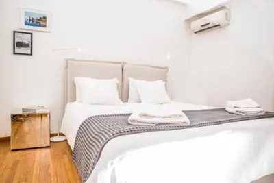 a white bedroom with a bed with white sheets and pillows at Flat White in Athens