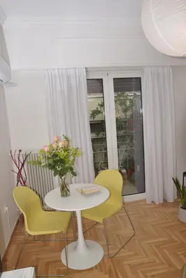 a white table with yellow chairs and a vase of flowers at Flat White in Athens