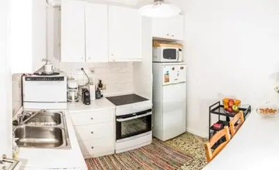 a kitchen with white cabinets and a white refrigerator at Flat White in Athens