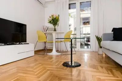 a living room with a couch and a table and yellow chairs at Flat White in Athens