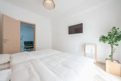a white bedroom with a bed and a potted plant at Athenian home near Acropolis in Athens