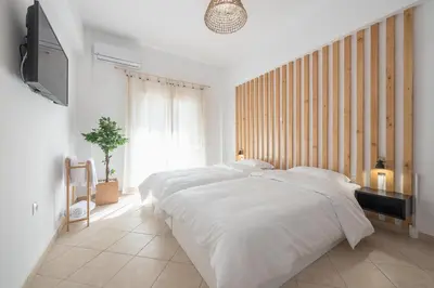 a white bedroom with a bed and a flat screen tv at Athenian home near Acropolis in Athens
