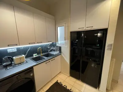 a kitchen with white cabinets and a black refrigerator at Minimal Central 2BR in Athens