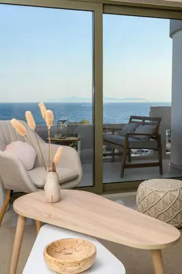 a living room with a table and a view of the ocean at Glyfada Cove Apartments-Ostria in Athens
