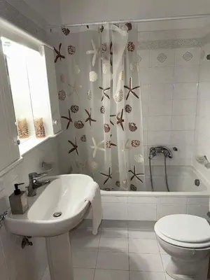 a bathroom with a sink and a toilet and a shower curtain at Art Blue Residence-Apartment Athens in Aghia Marina