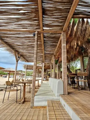 a wooden pavilion with tables and chairs on a beach at Art Blue Residence-Apartment Athens in Aghia Marina