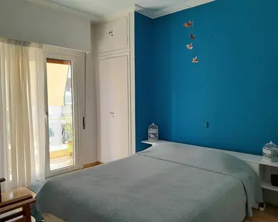 a blue bedroom with a bed and a window at Victoria Flat in Athens