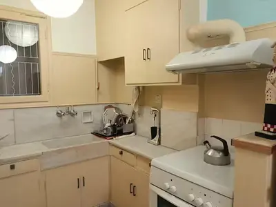 a small kitchen with white cabinets and a window at Victoria Flat in Athens