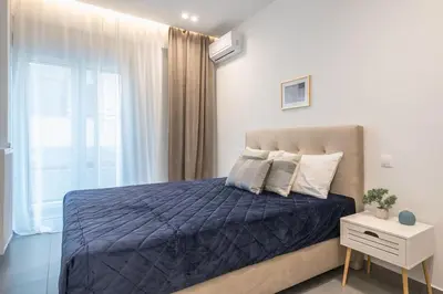 a bedroom with a bed with a blue comforter and a window at Minimal Harmony Apartment - Nea Smyrni by ΜΡS in Athens
