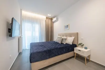 a bedroom with a blue bed and a tv at Minimal Harmony Apartment - Nea Smyrni by ΜΡS in Athens