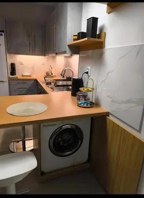 a kitchen with a washing machine under a counter at Stylish Urban Studio στο Γουδί in Athens