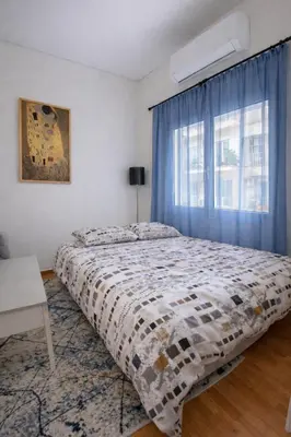 a bedroom with a bed and a window with blue curtains at Minimal Urban Apartment near Kolonaki in Athens
