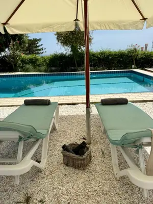 two chairs and an umbrella next to a swimming pool at ART BLUE RESIDENCE Pool in Aghia Marina