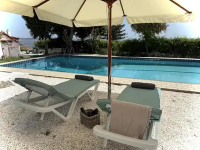 two chairs and an umbrella next to a swimming pool at ART BLUE RESIDENCE Pool in Aghia Marina