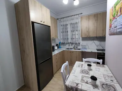 a kitchen with a table and a black refrigerator at Gousa Urban Stay 2 Min Walk to Metro in Athens