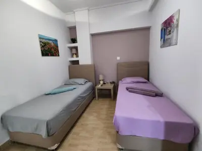 two beds in a room with purple and gray sheets at Gousa Urban Stay 2 Min Walk to Metro in Athens