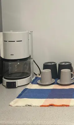 a toaster oven and two cups and a towel at Κομψό Διαμέρισμα στο Πασαλιμάνι in Piraeus