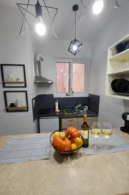 a bowl of fruit on a table with two glasses of wine at Cozy Estia in Athens