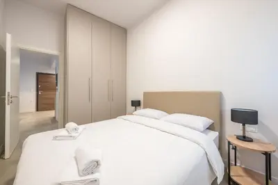 a white bedroom with a large bed with white sheets at Zografou Urban Apartments, A2Zen in Athens